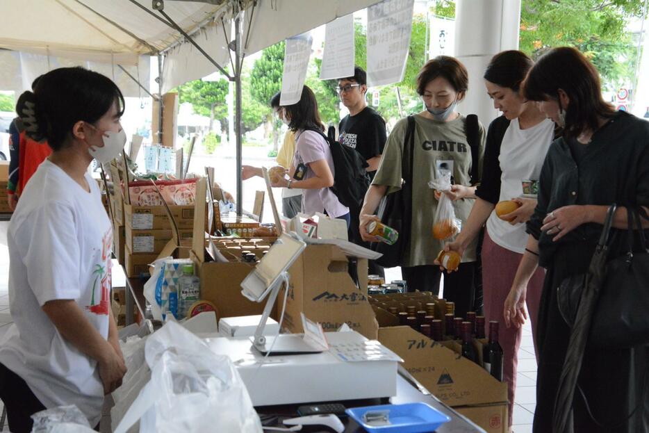 ずらりと並ぶ商品を楽しそうに選ぶ来場者ら＝２５日、那覇市泉崎の琉球新報社