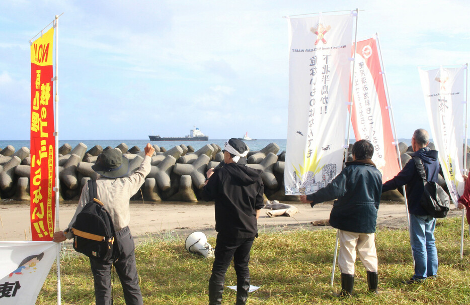 東京電力柏崎刈羽原発から搬出された使用済み核燃料を載せた運搬船が２６日、青森県むつ市の港に接岸した。港を望む近くの海岸では受け入れに反対する市民ら約１０人が「核のごみを持ち込むな」と抗議した＝同日午前