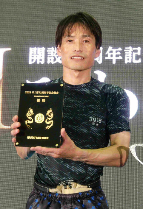 優勝メダル入りの盾を手に白い歯を見せる深井利寿（カメラ・早野　智之）