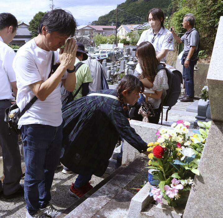 久保山愛吉さんが亡くなってから70年、静岡県焼津市内にある墓に献花し、手を合わせる人ら＝23日午前