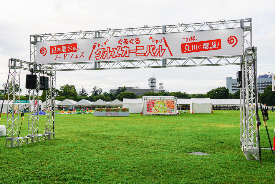 会場の目印は芝生エリア「ゆめひろば」の前に立つ「ぐるぐるグルメカーニバル in 立川」のゲート