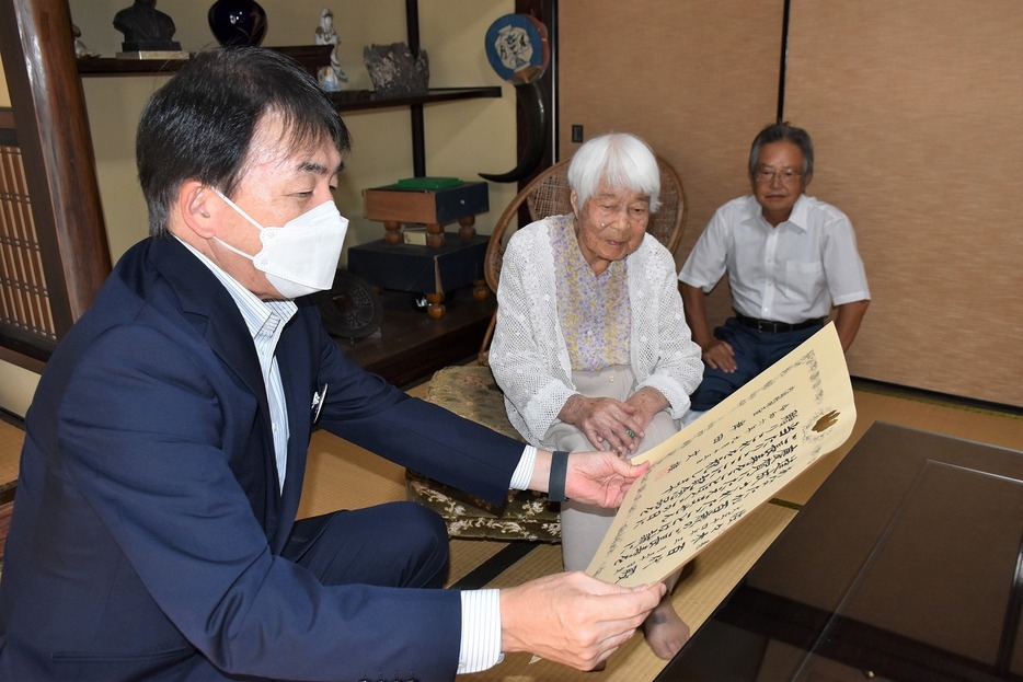 祝い状を藤田市長と読む佐々木さん（中央、梶上の佐々木さん宅で）