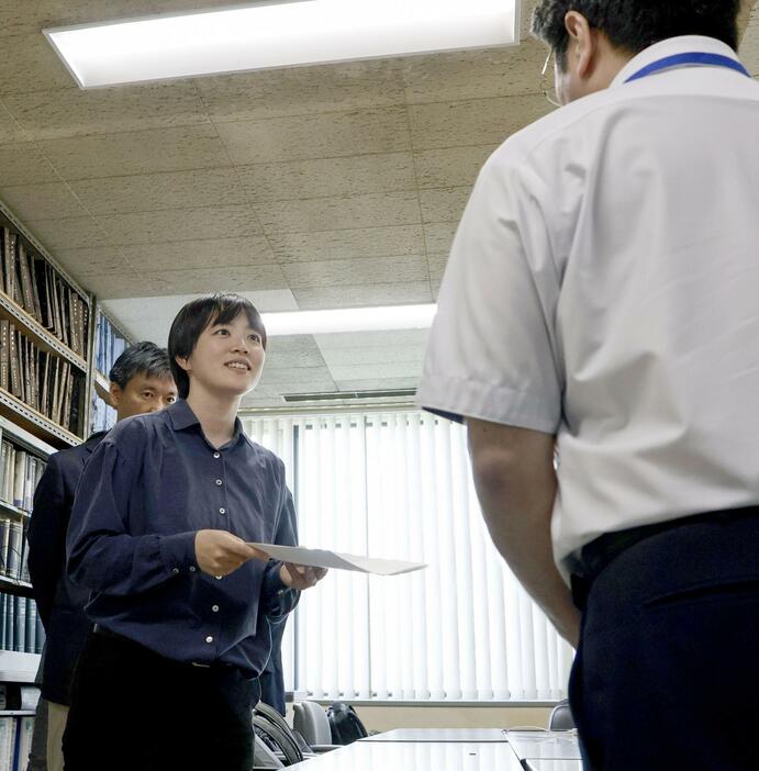 北海道の鈴木直道知事に対して謝罪などを求める要請書を、道の担当者（右）に提出する桃井希生さん＝9日午後、道庁