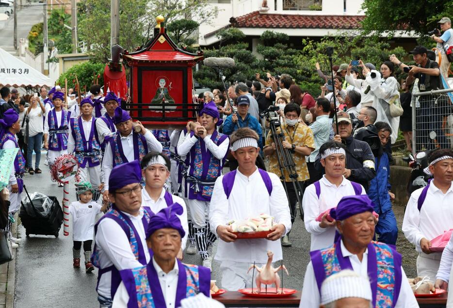 龕屋に向けて、龕（中央）を運んで道ズネーする住民ら＝11日午後４時18分、豊見城市高安（小川昌宏撮影）