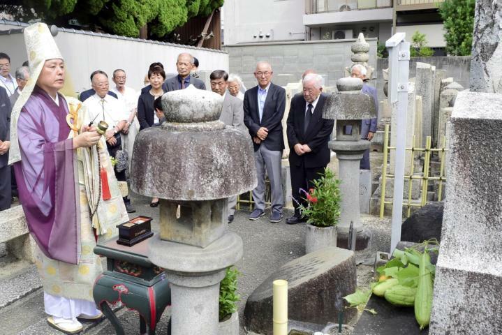 正岡子規の功績をしのんだ法要。埋髪塔（右）の前にはヘチマが供えられた＝19日午後、松山市末広町