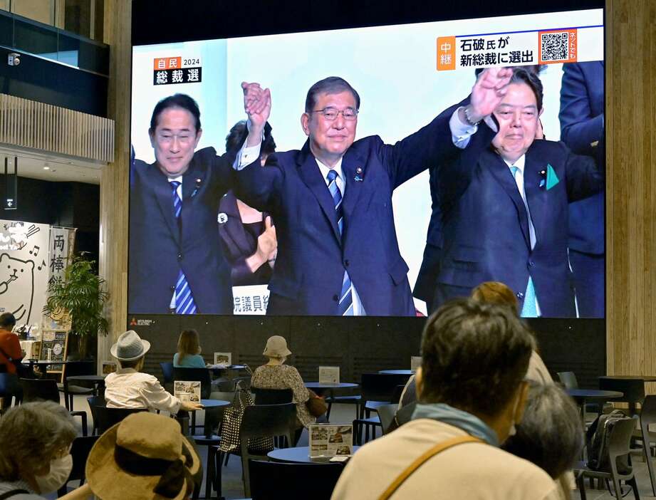 大型スクリーンに映し出される自民党総裁選を伝えるニュース＝２７日午後３時４０分、鹿児島市金生町のよかど鹿児島