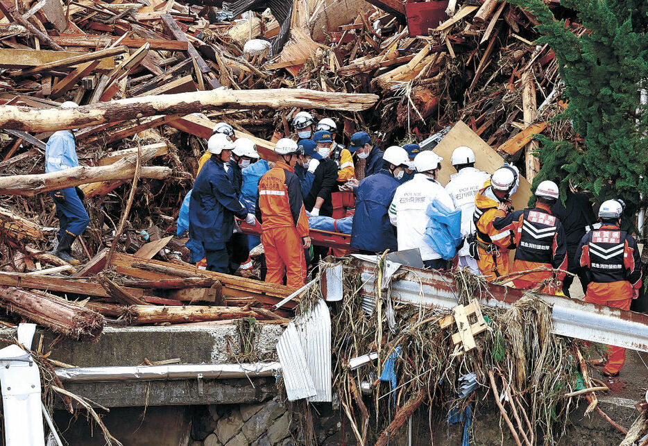 行方不明者を発見し、搬送する消防隊員＝２２日午後１時２５分、輪島市塚田町