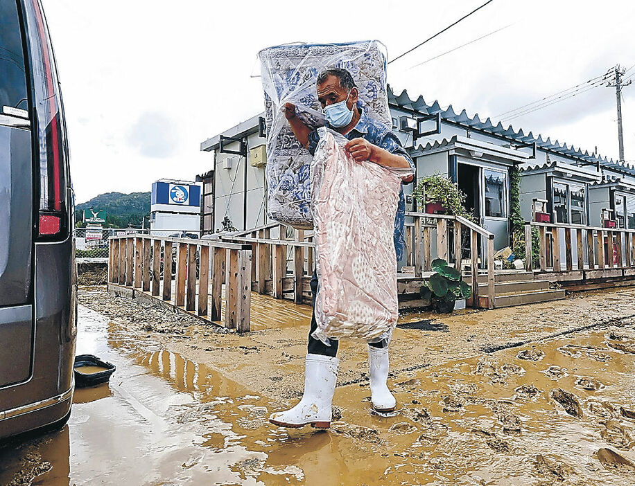 床上浸水した仮設住宅から布団を運び出す住民＝２２日午後２時１０分、輪島市宅田町