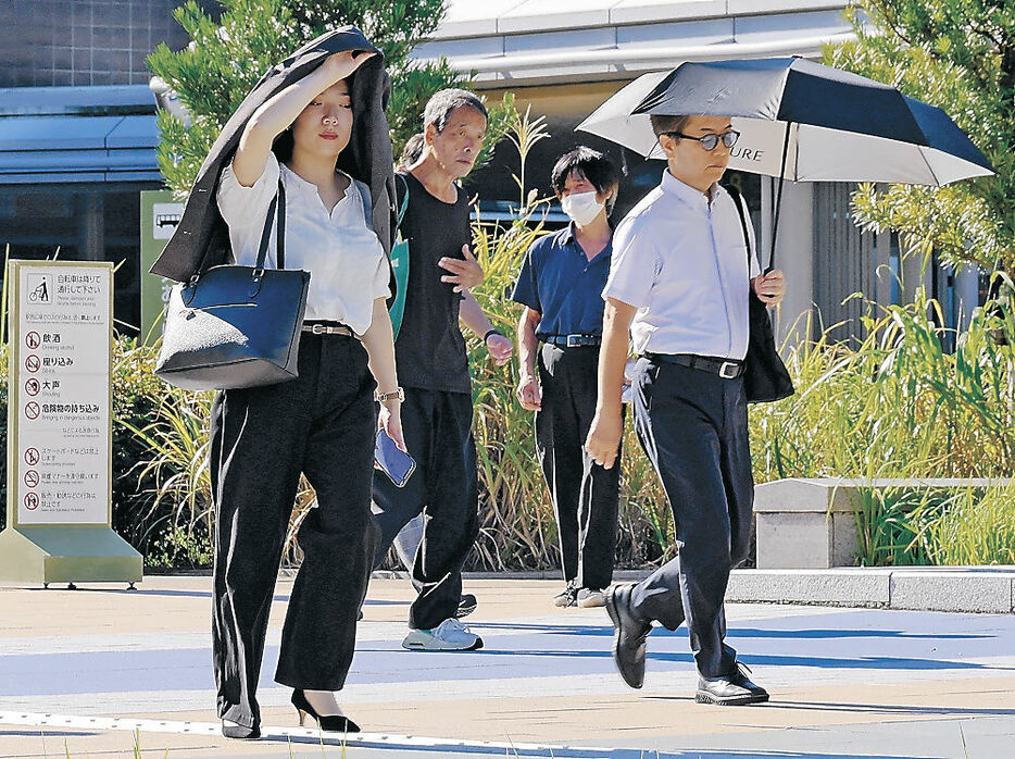 強い日差しを浴びながら出勤する人たち＝１０日午前８時４０分、金沢駅西口