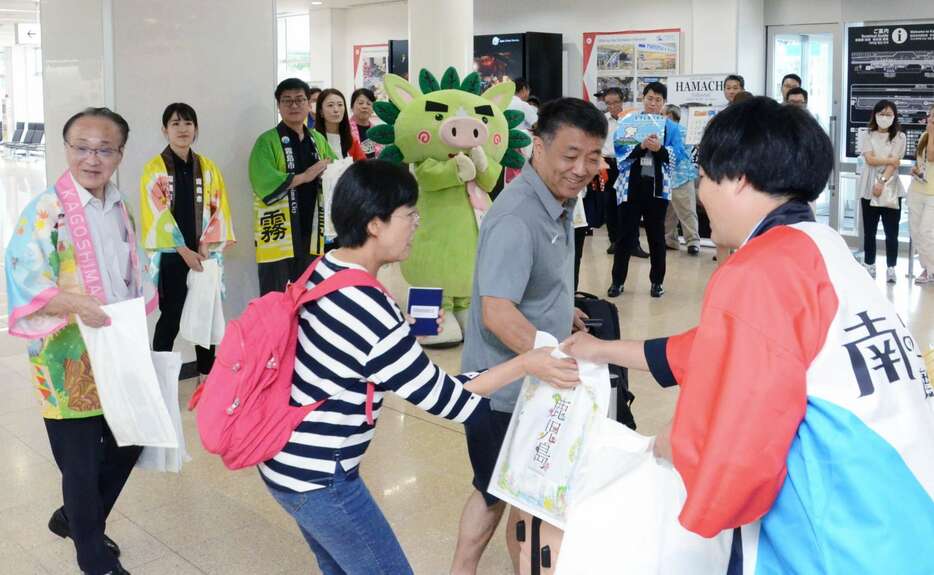 鹿児島の特産品が入った袋を受け取り、歓迎されるソウルからの乗客＝１４日、霧島市の鹿児島空港国際線ターミナル