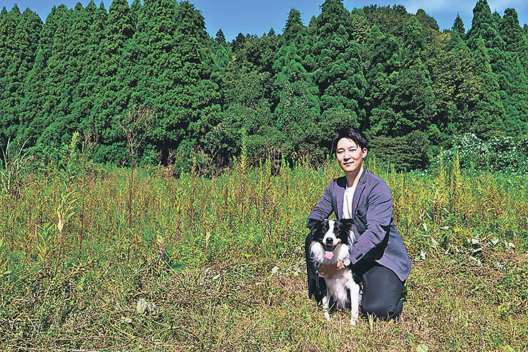 ふしきの森のオープンを進める場所で愛犬とともに笑顔を見せる中松さん=高岡市伏木矢田新町