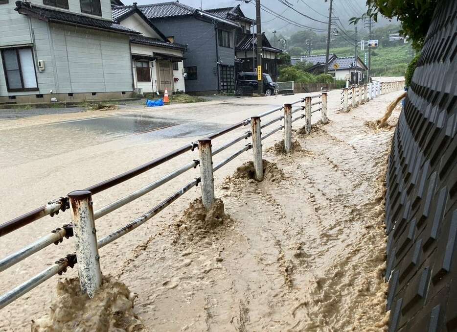 大雨で水があふれ、川のようになっている道路＝21日午前、石川県輪島市