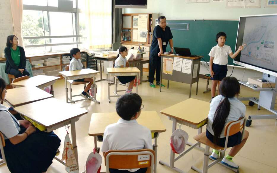 児童の発表を見守る小瀧弘規さん（中央）＝錦江町の田代小学校