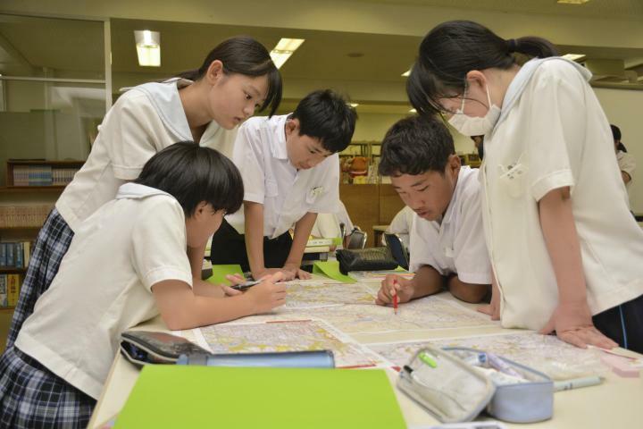 ハザードマップから災害警戒区域などを白地図に転記する生徒ら＝25日午後、松山市溝辺町