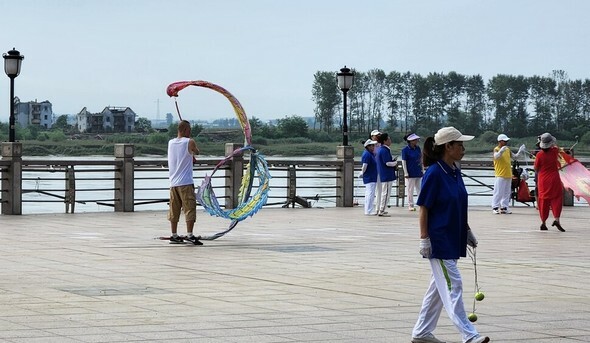 2024年8月下旬のある日、中国遼寧省丹東の江辺公園では、丹東の市民たちが普段通り朝の体操をしているが、対岸の威化島下端里の壊れた家は、強い夏の日差しの下でも色を失っている。苦痛は分かち合い難し