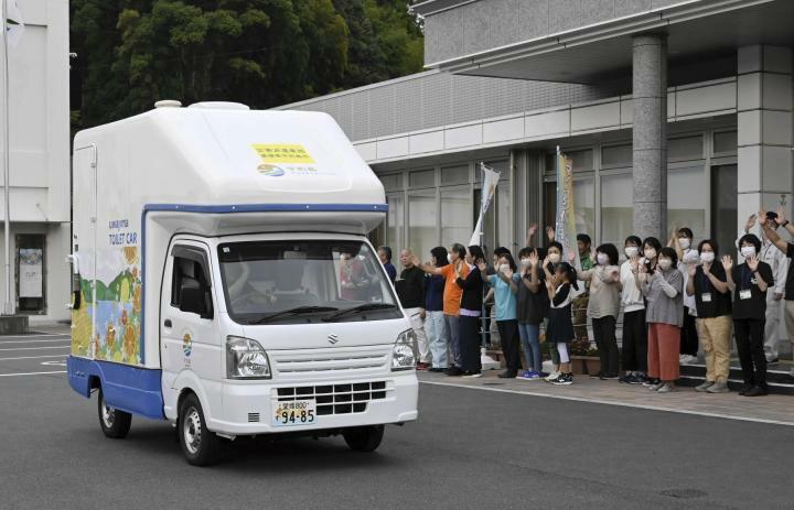 能登半島へ出発するトイレカーを見送る職員ら＝25日午後5時半ごろ、宇和島市三間町宮野下