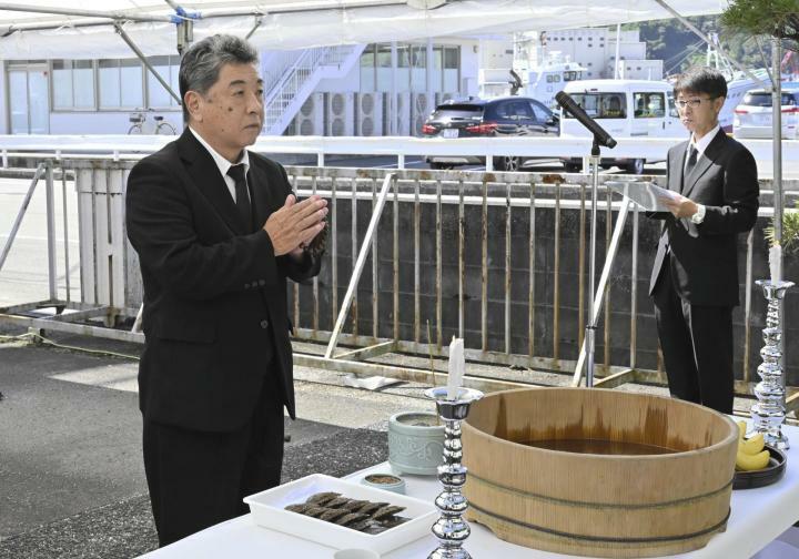 真珠貝供養祭で供養塔に手を合わせる県漁協の平井義則組合長（左）＝24日午前、宇和島市築地町2丁目