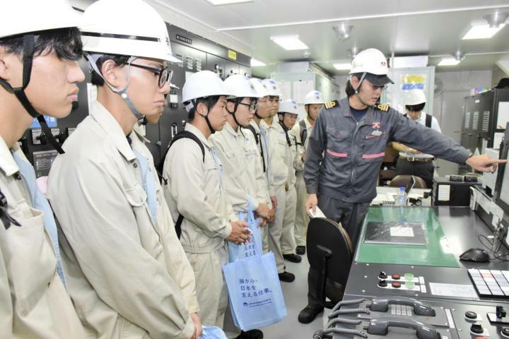 タンカー内で船員（右）の話を真剣な表情で聞く学生＝9日午前、松山市三津ふ頭