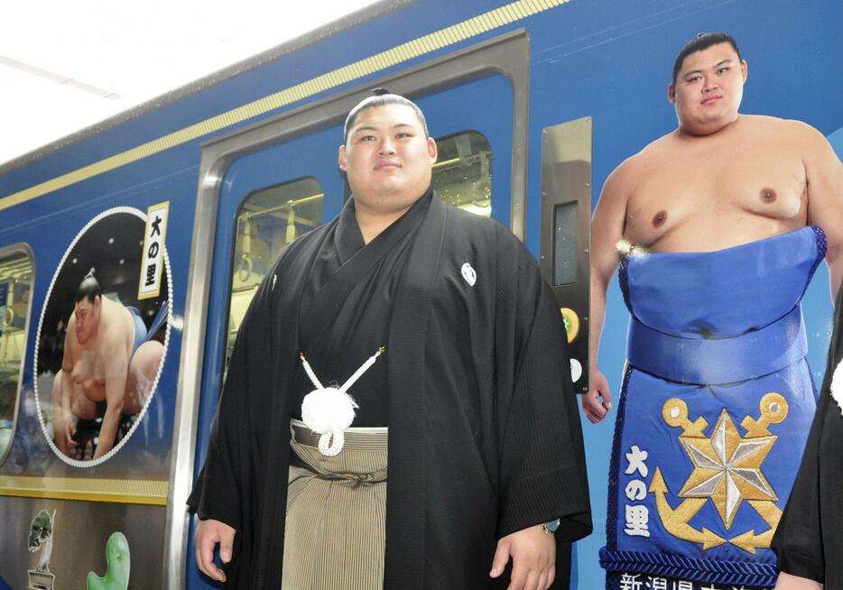 自身の写真などで装飾されたラッピング車両の前で撮影に応じる新大関大の里＝28日、新潟県糸魚川市