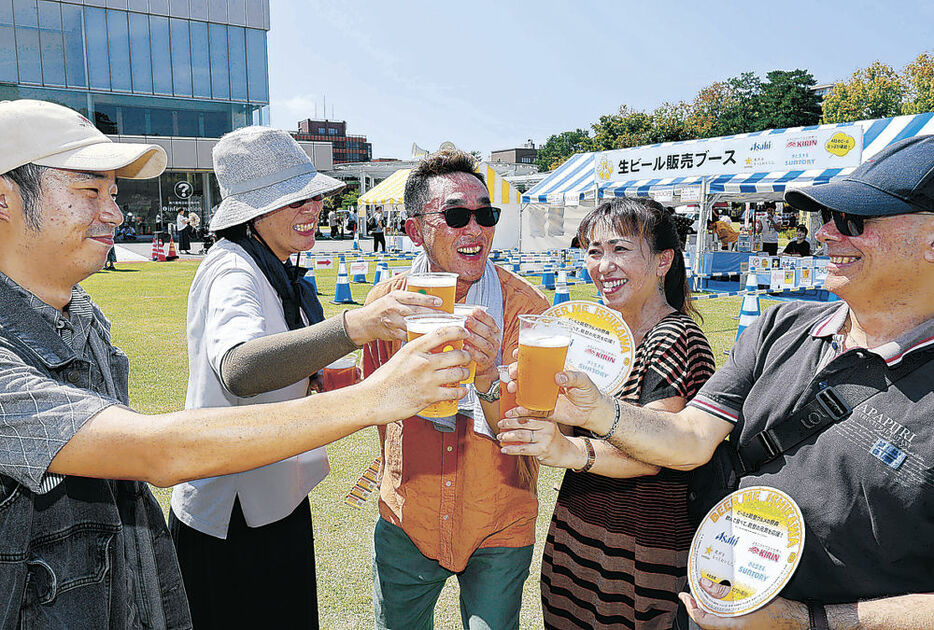 冷たいビールで乾杯する来場者＝１４日午前１１時１０分、金沢市のしいのき迎賓館石の広場