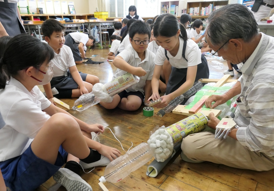 地域のお年寄りたちと協力して製作に励む子どもたち=岡山県津山市で