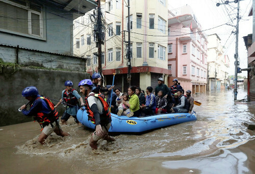 大雨で氾濫した川の堤防付近の浸水地域から救出される住民（２８日、ネパール首都カトマンズで）=ロイター