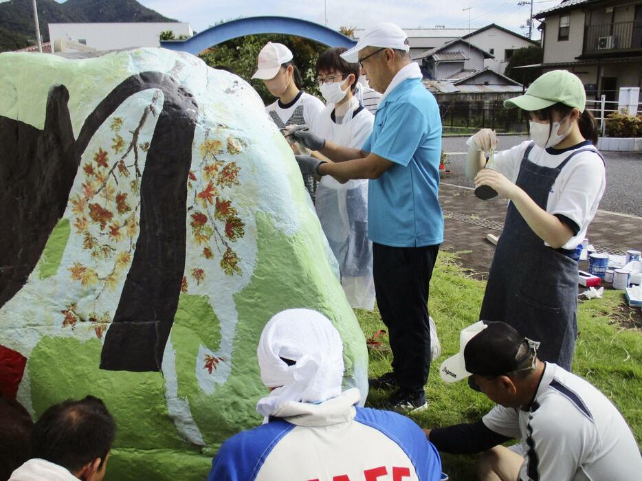 ストーンアートの修復作業を行う広島県大竹市立玖波中の美術部員と近隣住民＝2023年9月、広島県大竹市（同校提供）