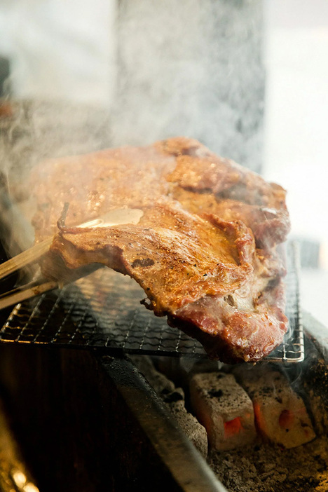 厨房の奥の窯で焼いた後、最終仕上げに表面を炙り、食べやすいサイズにカットして卓上へ。