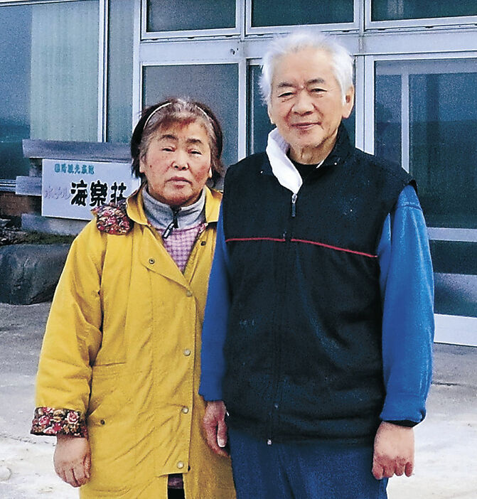 海楽荘の前で写真に納まる池田幸雄さん（右）と妻真里子さん＝１月３１日、珠洲市真浦町