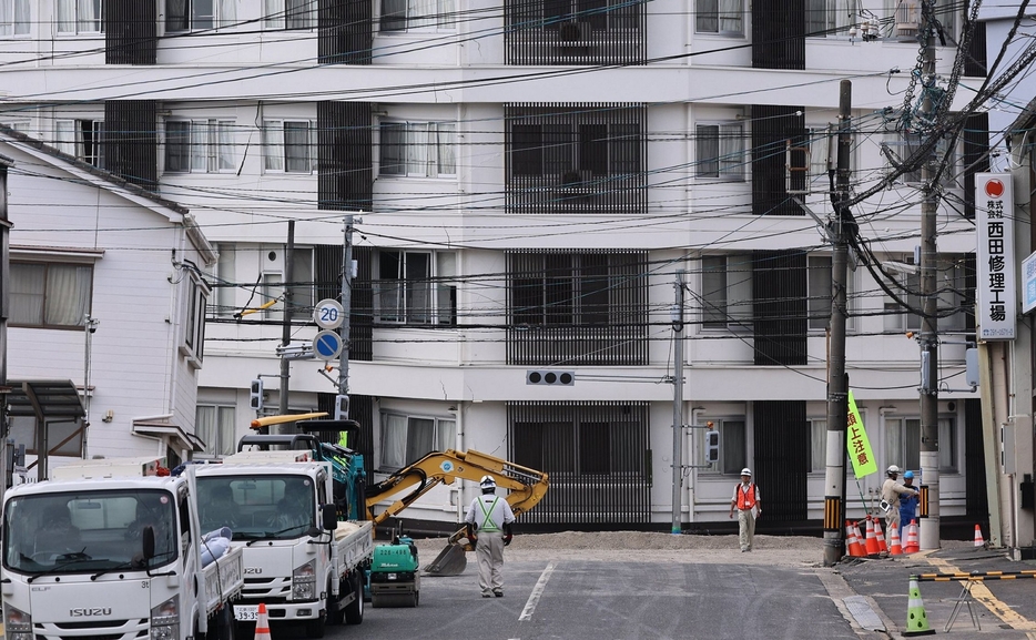 道路の埋め戻しが進み、周囲の建物の傾きがより分かる陥没現場＝28日午後0時47分、広島市西区