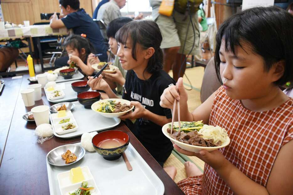 西之表市産の牛肉を使った肉うどんを食べる子どもたち＝同市西之表の美浜町自治公民館