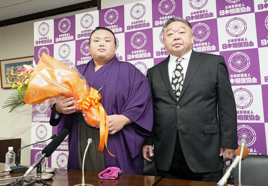 現役引退の記者会見で、花束を手にする元大関貴景勝。右は常盤山親方＝21日、東京・両国国技館