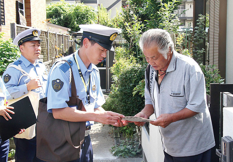 交通事故の現場付近で住民に注意喚起をする警察官＝9日午後、三郷市戸ケ崎