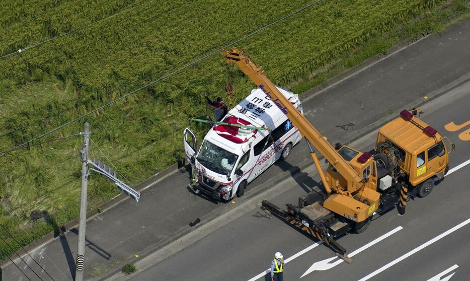 交差点で乗用車と衝突し、転落した田んぼから引き上げられた救急車＝9日午後0時57分、三重県鈴鹿市（共同通信社ヘリから）