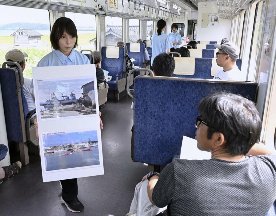 のと鉄道の「語り部列車」で、津波被害の写真を載せたパネルを乗客に見せる乗務員＝16日午前（代表撮影）