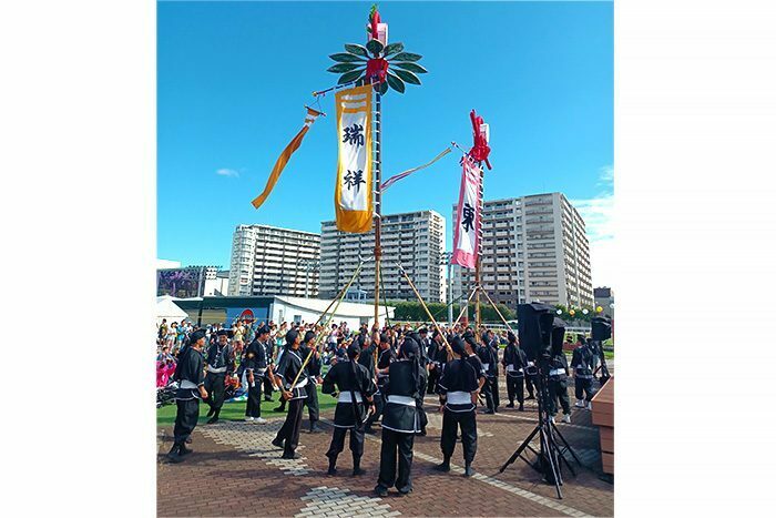 復刻した安里の旗頭（左）と牧志の旗頭を競い合うように掲げる有志団のメンバー＝16日、神奈川県川崎市の川崎競馬場