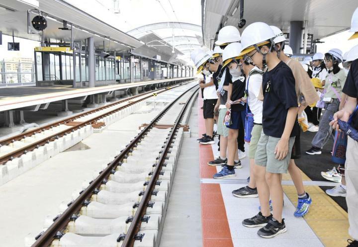 高架化されたホームでレールなどの設備を見学する児童＝13日午前、松山市南江戸1丁目