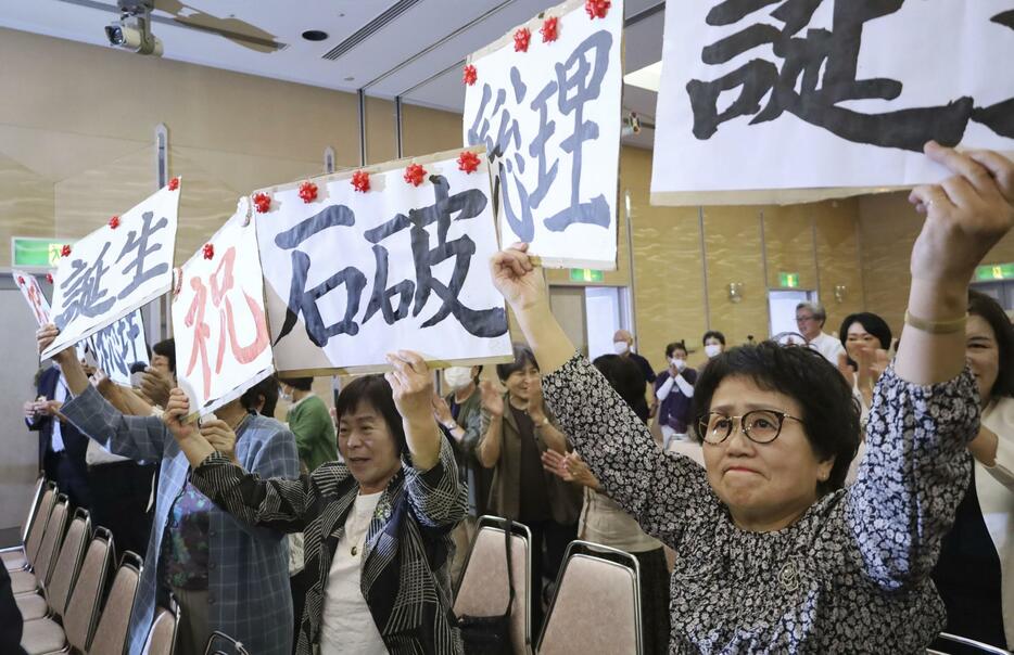 石破茂氏が自民党の新総裁に選出され、ボードを掲げる支援者ら＝27日午後、鳥取市