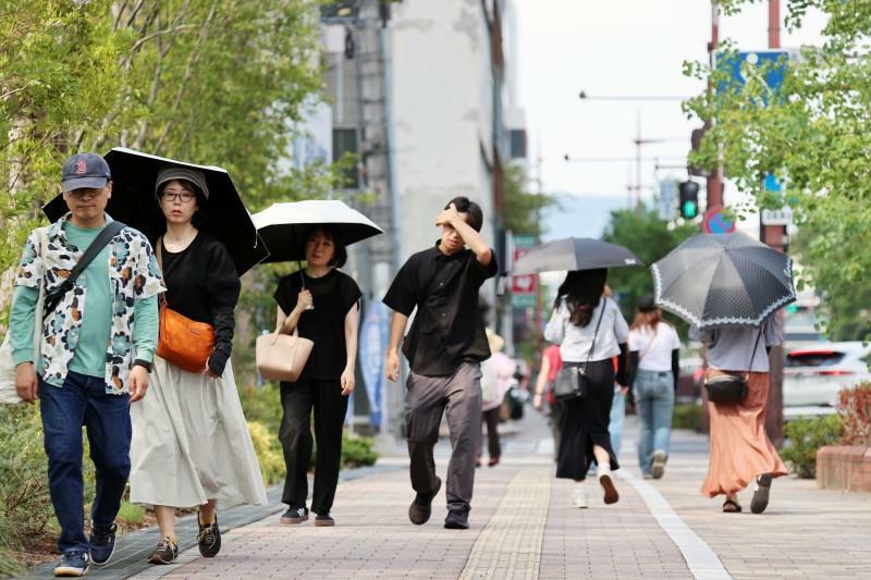 日傘を手に歩く通行人。年間最多日数となった高梁市など岡山県内各地で猛暑日を観測した＝8日午後2時12分、岡山市中心部