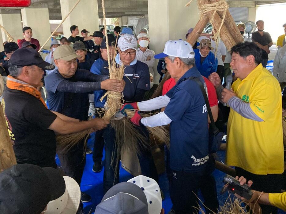 金武町大綱曳の本番に向けて綱作りをする区民ら＝8月24日、金武町営体育館下駐車場