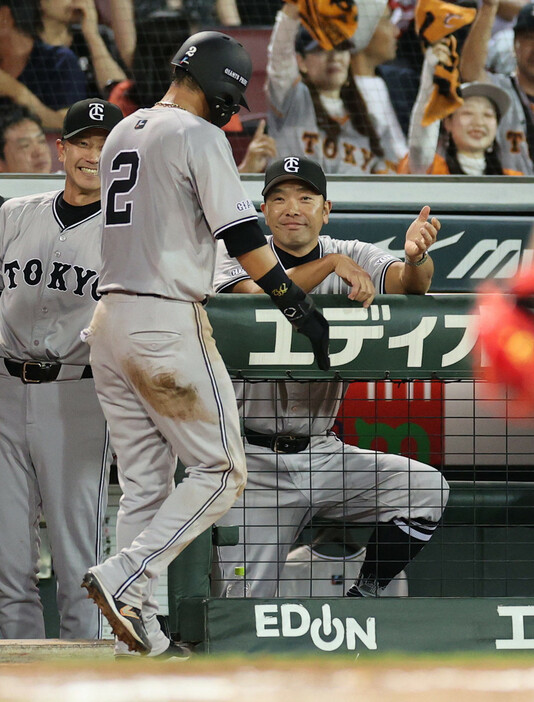 ６回、巨人・岡本和の適時二塁打で生還した吉川（手前）を迎える阿部監督（右奥）＝２８日、マツダスタジアム