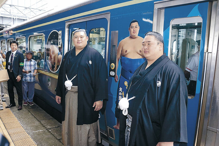 お披露目されたラッピング電車を前に写真撮影に応じる大の里（左）と欧勝海＝新潟県糸魚川市