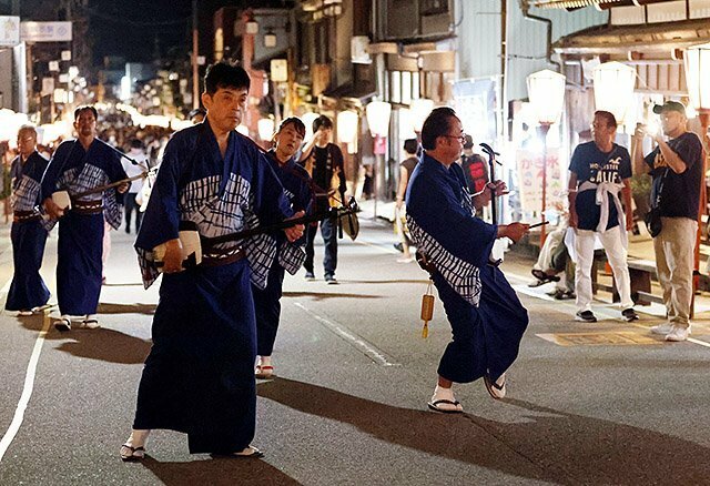 地方衆が胡弓や三味線を奏でながら通りを歩き始め、観光客が聞き入った＝上新町