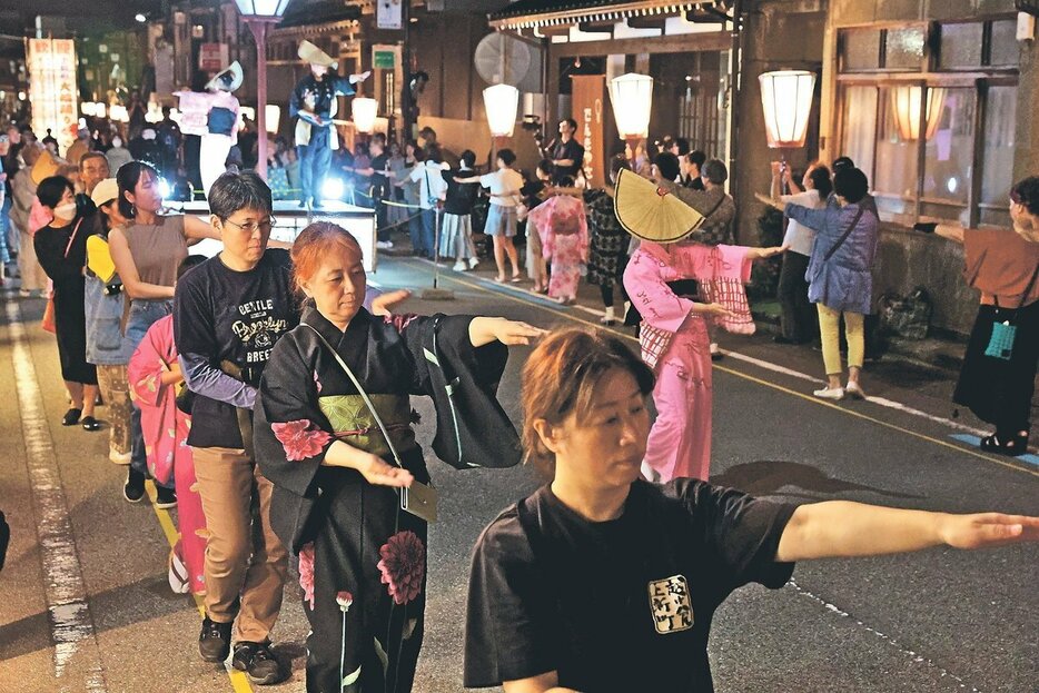 踊り手と一緒に通りで「大輪踊り」を堪能する観光客ら＝３日午後１０時半ごろ、富山市八尾町上新町