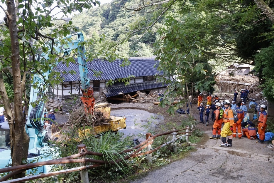 石川県能登町の北河内地区で、がれきの撤去作業を見守る消防隊員ら＝25日