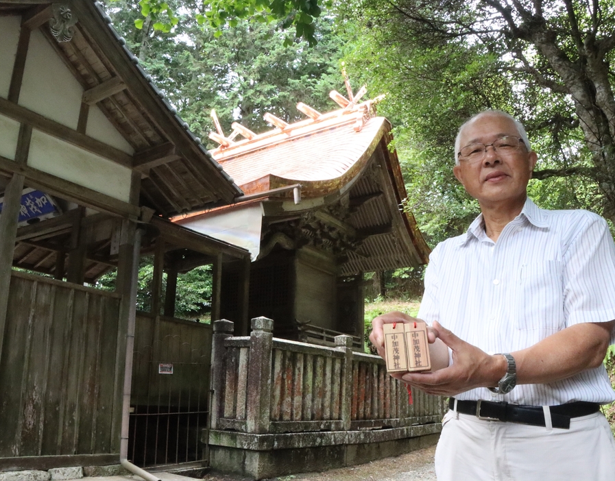 垂木で手作りしたお守りを手に、遷座行事とコンサートへの来場を呼びかける塩見さん＝兵庫県丹波市市島町中竹田で