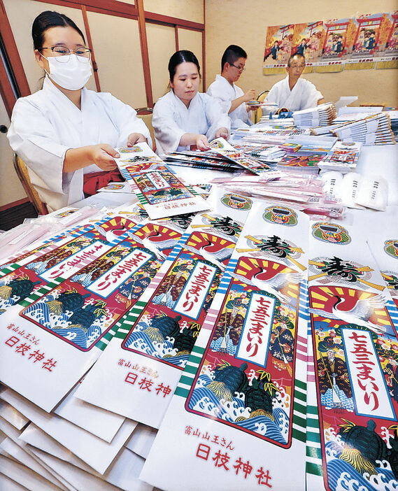 七五三に向けて千歳飴などを袋詰めする神職＝富山市の日枝神社