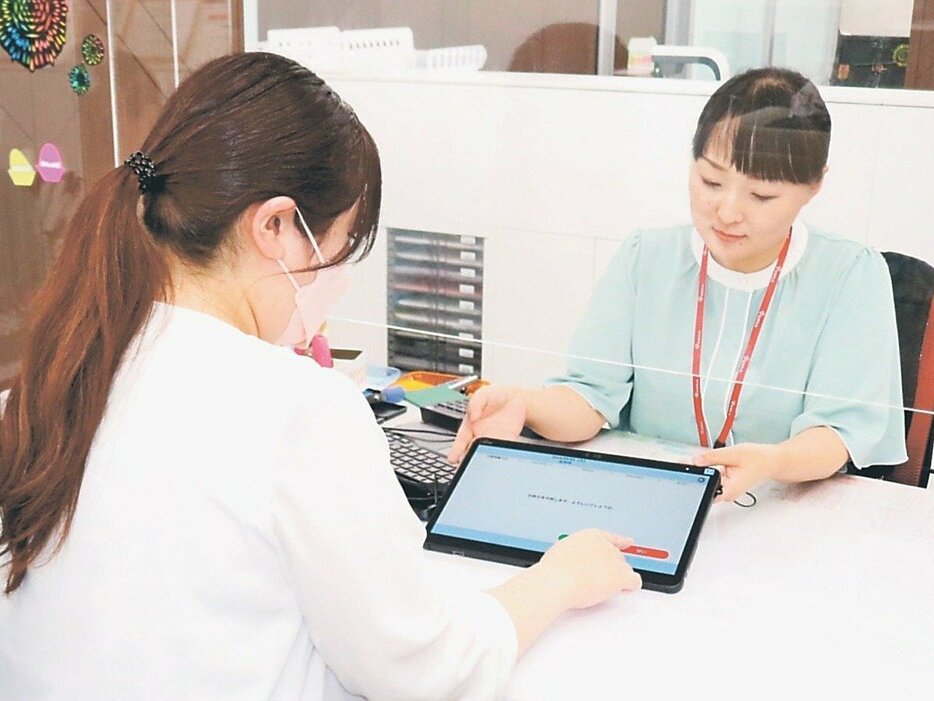 ローカウンターでタブレット端末を示す職員＝高岡信金美幸町支店