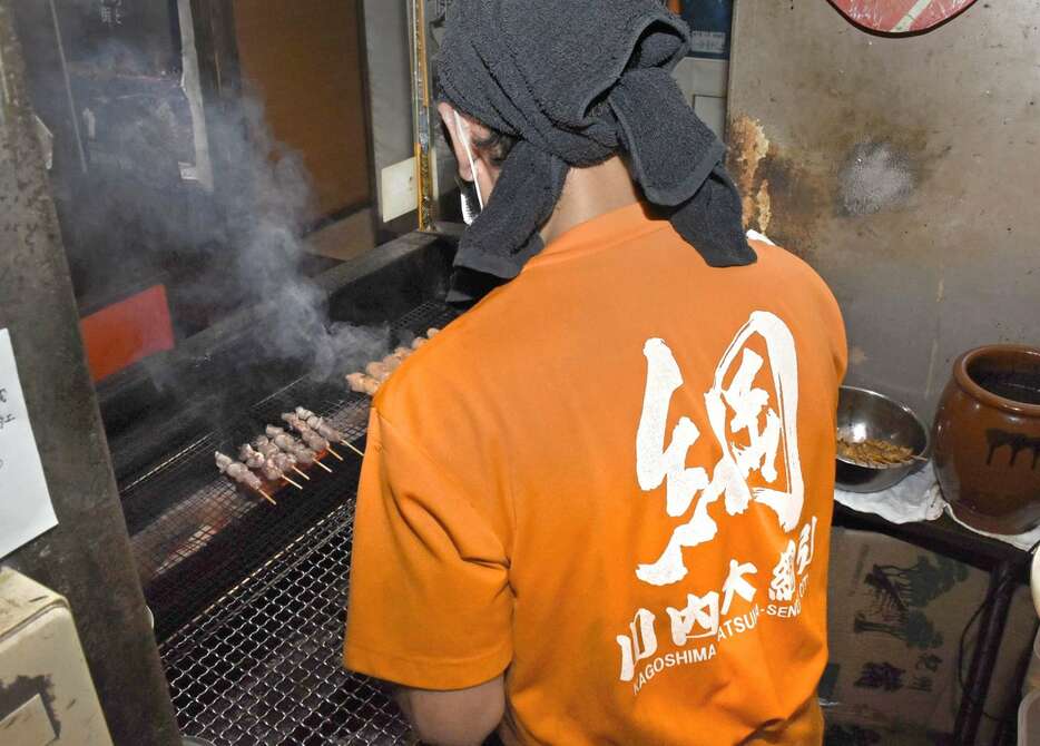 年間を通じて川内大綱引のＴシャツを着て接客する飲食店＝１９日、薩摩川内市の「炭匠だん」