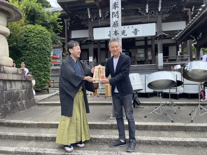 「岐阜まち家守」社長の山本慎一郎さん（左）から「岐阜町　家持町人」と記された手形を受け取る秋元祥治さん（岐阜まち家守提供）＝２０２４年６月、岐阜市